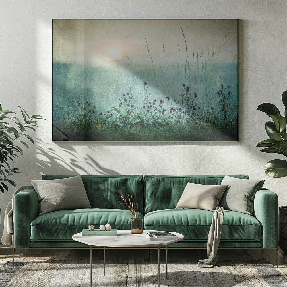 A framed photograph of a misty meadow at sunrise. The soft, pale sun hangs in a hazy, textured sky. In the foreground, tall green grasses and small purple wildflowers are in soft focus, creating a serene and dreamy atmosphere. Decor
