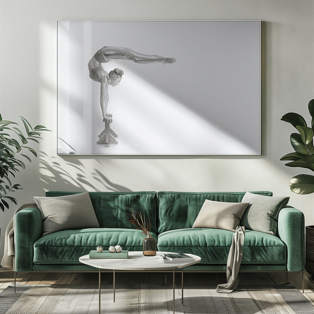 A framed black and white photograph of a female gymnast with a metallic silver-painted body, balancing in a difficult handstand pose on small blocks against a stark white background. Her back is arched and her legs are extended straight out behind her, parallel to the ground. Artwork