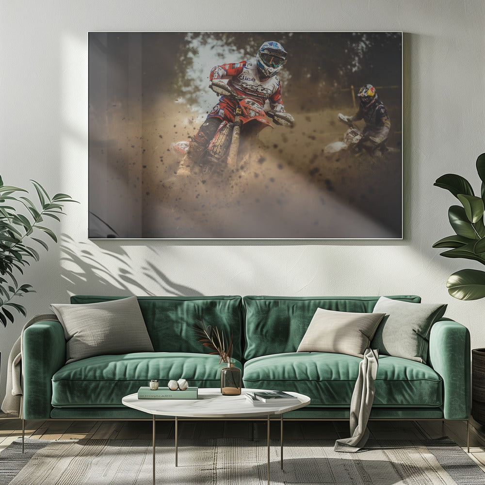An action shot of a motocross rider in red, white, and blue gear, speeding through a dusty turn on a dirt track, kicking up a large cloud of mud and debris. Another racer is visible in the background. The image is presented within a silver frame. Print