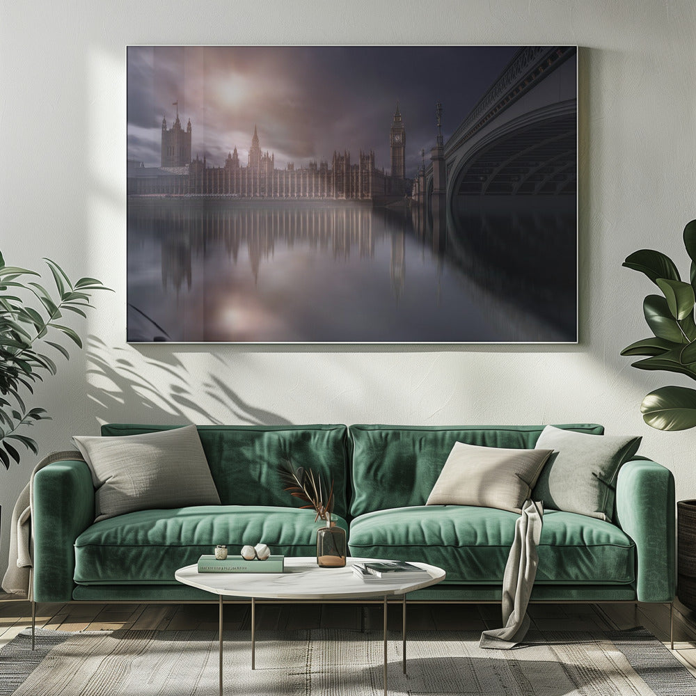 A dramatic, atmospheric photograph of the Houses of Parliament and Big Ben in London, reflected in the still waters of the River Thames. A bright sun breaks through dark, moody clouds, casting a warm light on the scene, with a stone bridge visible to the right. The image is enclosed in a silver frame. Print