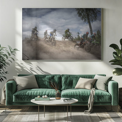 A dynamic action shot of several motocross riders racing up a dirt hill, kicking up a large cloud of dust. The riders are in full gear on colorful bikes, with a dramatic cloudy sky and a tall tree in the background. Print