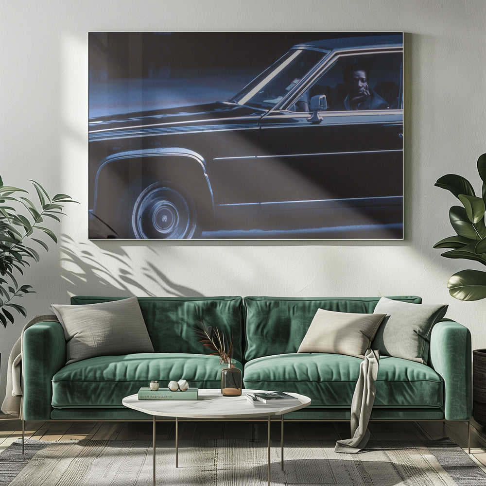 A moody, blue-toned photograph of a Black man sitting pensively in the driver's seat of a dark vintage sedan at night, framed in silver. Poster