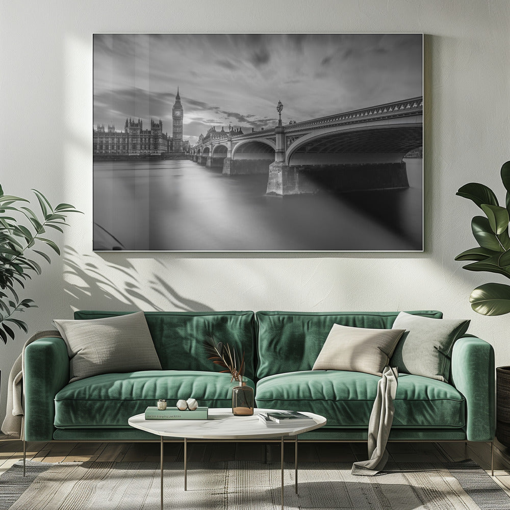 A dramatic black and white long-exposure photograph of London, featuring the smooth River Thames in the foreground, Westminster Bridge on the right, and the iconic Big Ben and Houses of Parliament on the left under a cloudy, streaked sky. The image is presented in a silver frame. Print