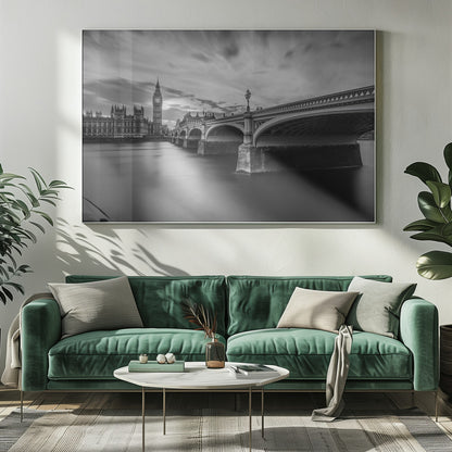 A dramatic black and white long-exposure photograph of London, featuring the smooth River Thames in the foreground, Westminster Bridge on the right, and the iconic Big Ben and Houses of Parliament on the left under a cloudy, streaked sky. The image is presented in a silver frame. Print