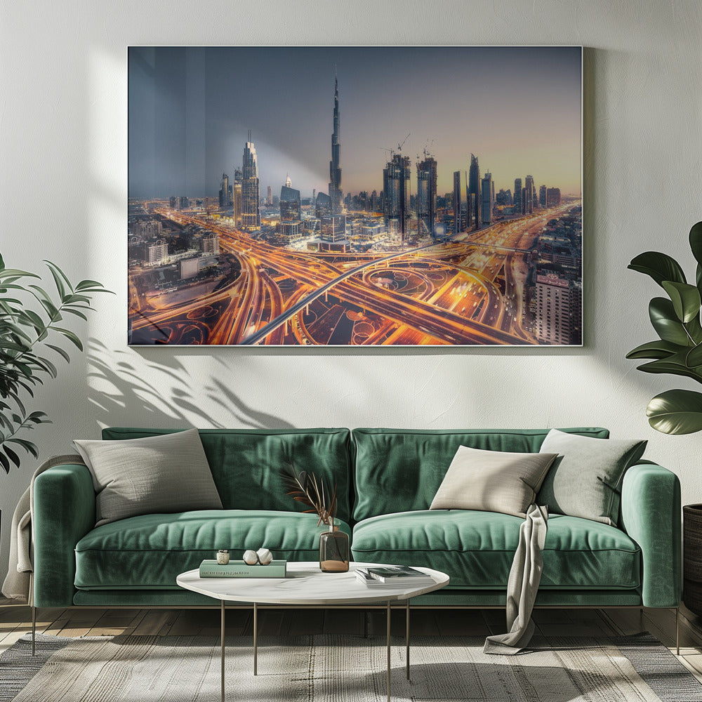 A wide-angle, elevated photograph of the Dubai skyline at dusk, with the iconic Burj Khalifa towering in the center. In the foreground, a complex network of highways glows with the orange light trails of moving traffic, while the city's numerous skyscrapers are illuminated against a twilight sky. Print