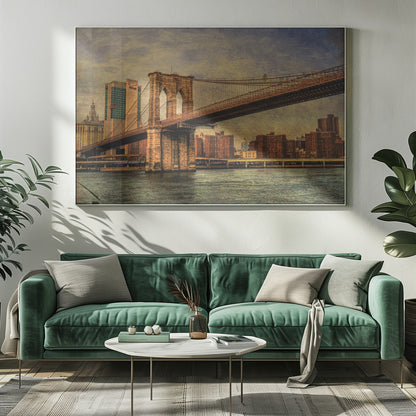 A framed, vintage-style photograph of the Brooklyn Bridge from a low angle, showing its stone pylon and suspension cables against a textured, cloudy sky. The Manhattan skyline and the East River are visible in the background and foreground. Wall Art