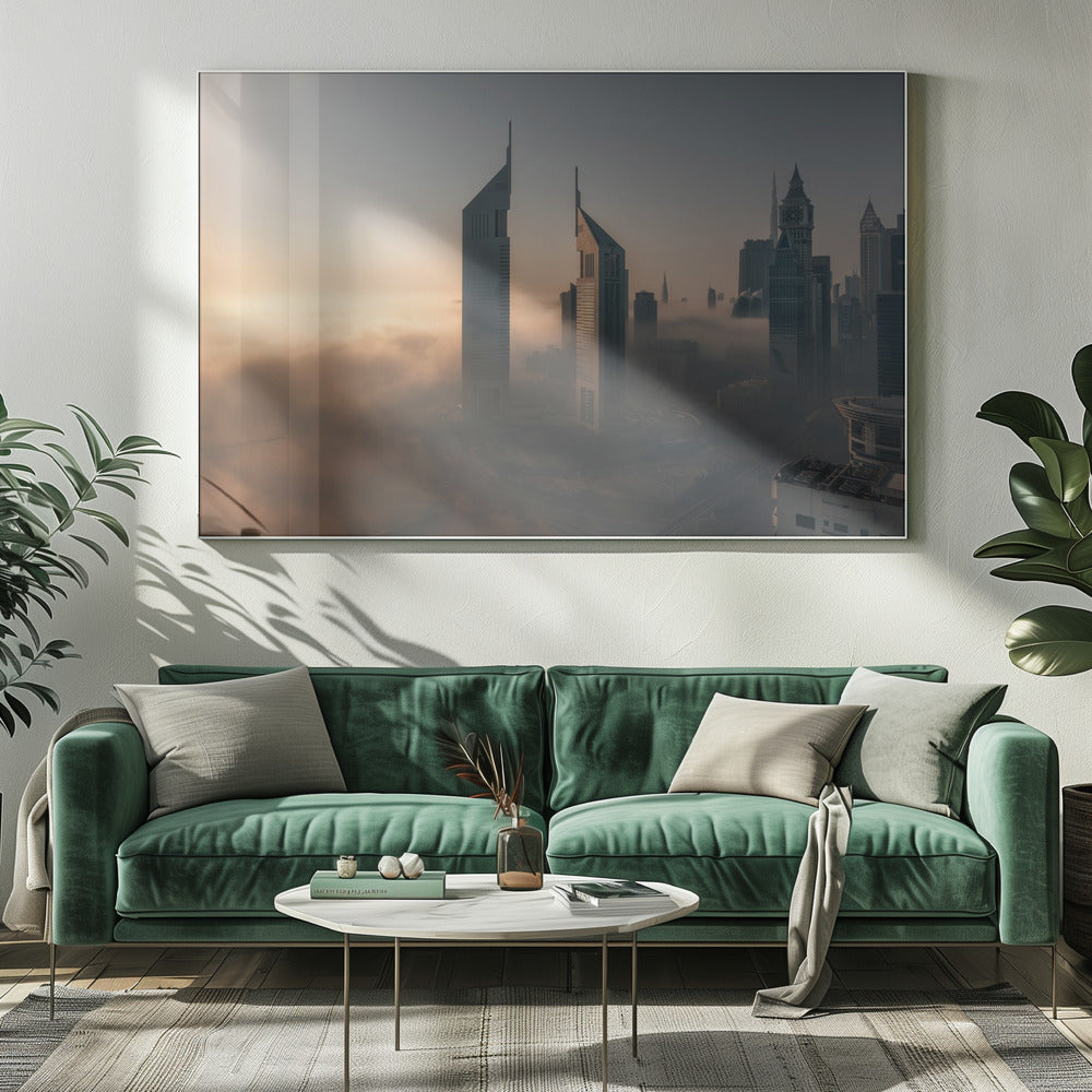 A framed aerial photograph of a futuristic city skyline, likely Dubai, enveloped in a thick layer of fog at sunrise. Tall, modern skyscrapers, including the iconic Emirates Towers, pierce through the clouds, with the warm light of the rising sun creating a hazy, golden glow on the left. Poster