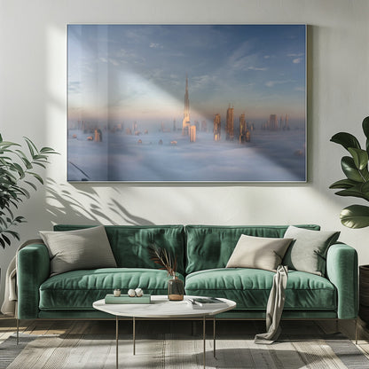 A framed photograph of the Dubai skyline, with the Burj Khalifa and other skyscrapers piercing through a thick blanket of low-lying clouds or fog. The scene is bathed in the warm, golden light of sunrise or sunset against a pale blue sky. Poster