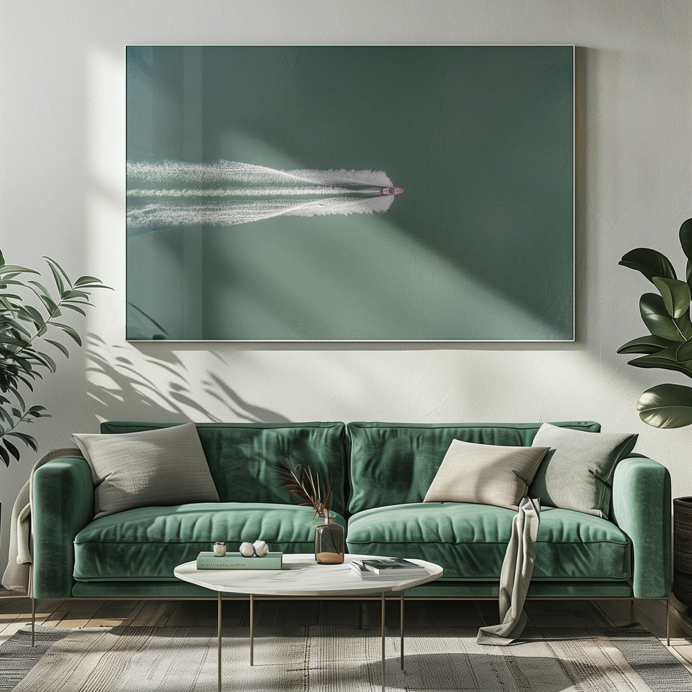 An aerial top-down photograph of a red motorboat speeding across a vast expanse of calm, green water, leaving a long, white, frothy wake behind it. The scene is presented within a simple silver frame. Print
