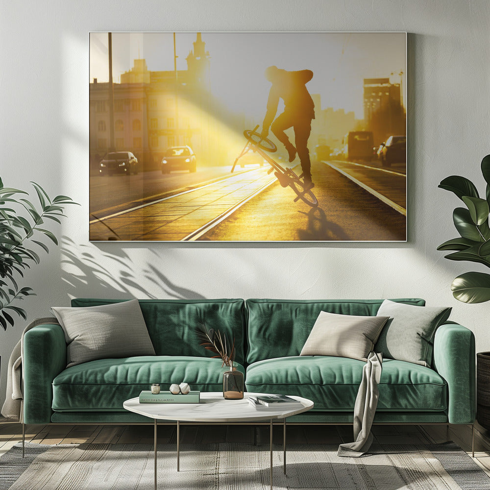 A silhouetted BMX rider performs a trick on a city street during a brilliant golden sunset, with the sun flaring behind them and casting long shadows on the tram tracks. Decor