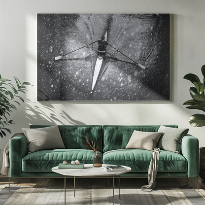 A dramatic black and white overhead photograph of a single rower in a narrow scull, captured mid-stroke as they cut through dark water during a heavy snowfall, creating a high-contrast and atmospheric scene. Decor