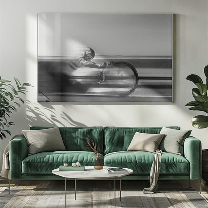 A black and white photograph captured with motion blur, showing a cyclist in an aerodynamic position racing at high speed. The background is blurred into horizontal lines, emphasizing the velocity. The image is enclosed in a silver frame. Wall Art
