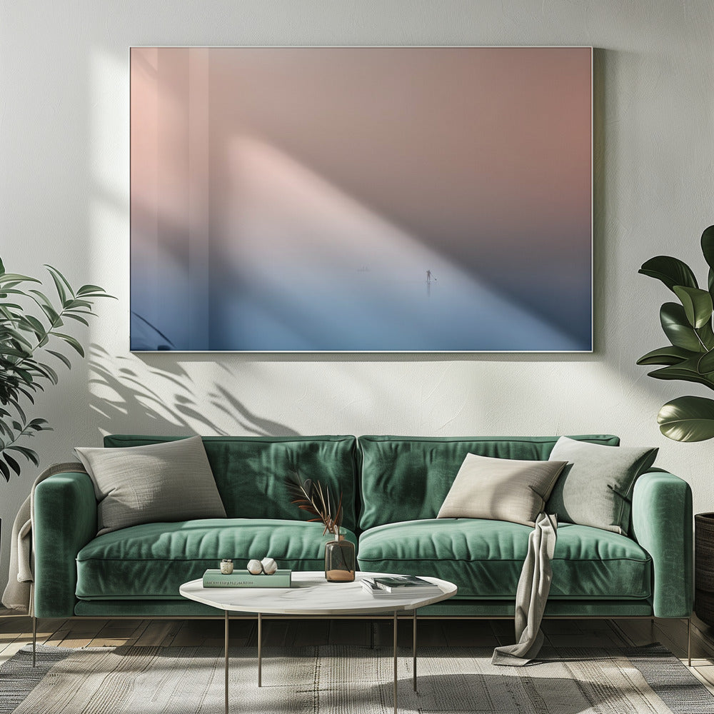 A minimalist framed photograph of a solitary person on a stand-up paddleboard, silhouetted against a vast, calm expanse of water under a hazy, gradient sky that shifts from soft pink to deep blue. Wall Art