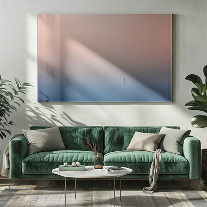 A minimalist framed photograph of a solitary person on a stand-up paddleboard, silhouetted against a vast, calm expanse of water under a hazy, gradient sky that shifts from soft pink to deep blue. Wall Art