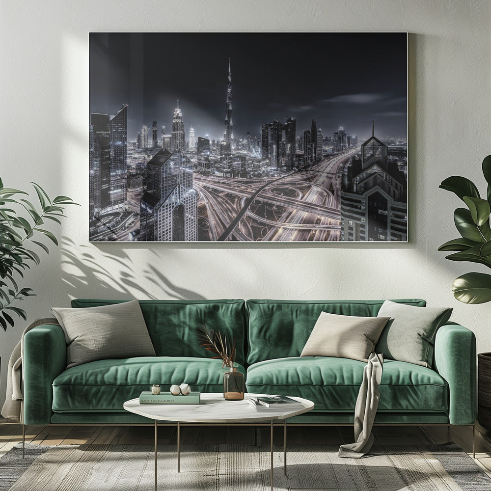 A striking black and white aerial photograph of the Dubai skyline at night, captured in a silver frame. The Burj Khalifa stands tall in the background, while a complex web of illuminated highway overpasses and light trails from traffic fills the foreground, creating a dynamic and futuristic cityscape. Print