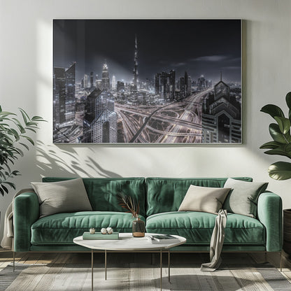 A striking black and white aerial photograph of the Dubai skyline at night, captured in a silver frame. The Burj Khalifa stands tall in the background, while a complex web of illuminated highway overpasses and light trails from traffic fills the foreground, creating a dynamic and futuristic cityscape. Print