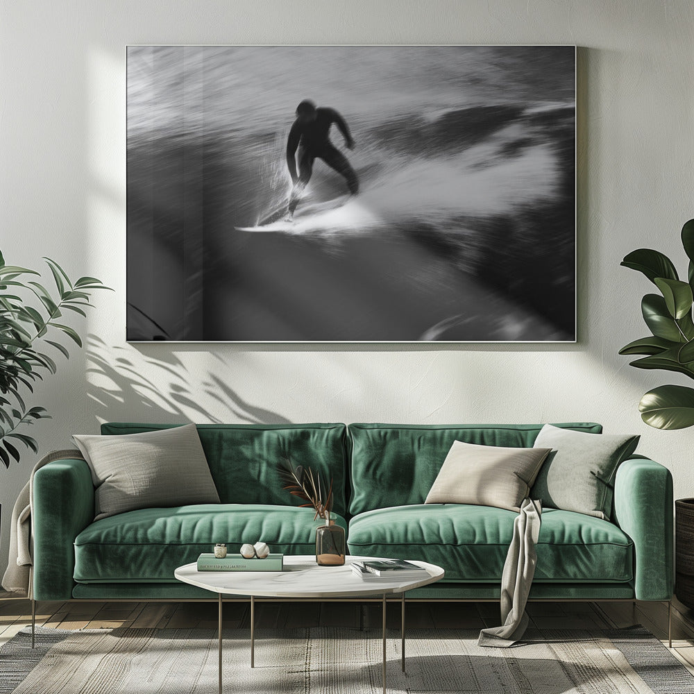 A dynamic black and white photograph of a surfer in a wetsuit carving through a wave. The image uses motion blur to emphasize the speed and energy of the water, creating a powerful and artistic effect. The artwork is presented in a simple silver frame. Print