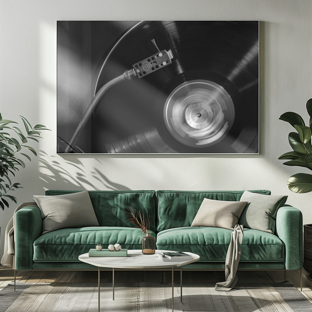 A framed, black and white, close-up photograph of a record player in action. The turntable is spinning a vinyl record, creating a motion blur on the center label. The tonearm and stylus are positioned over the grooved surface of the record. Poster