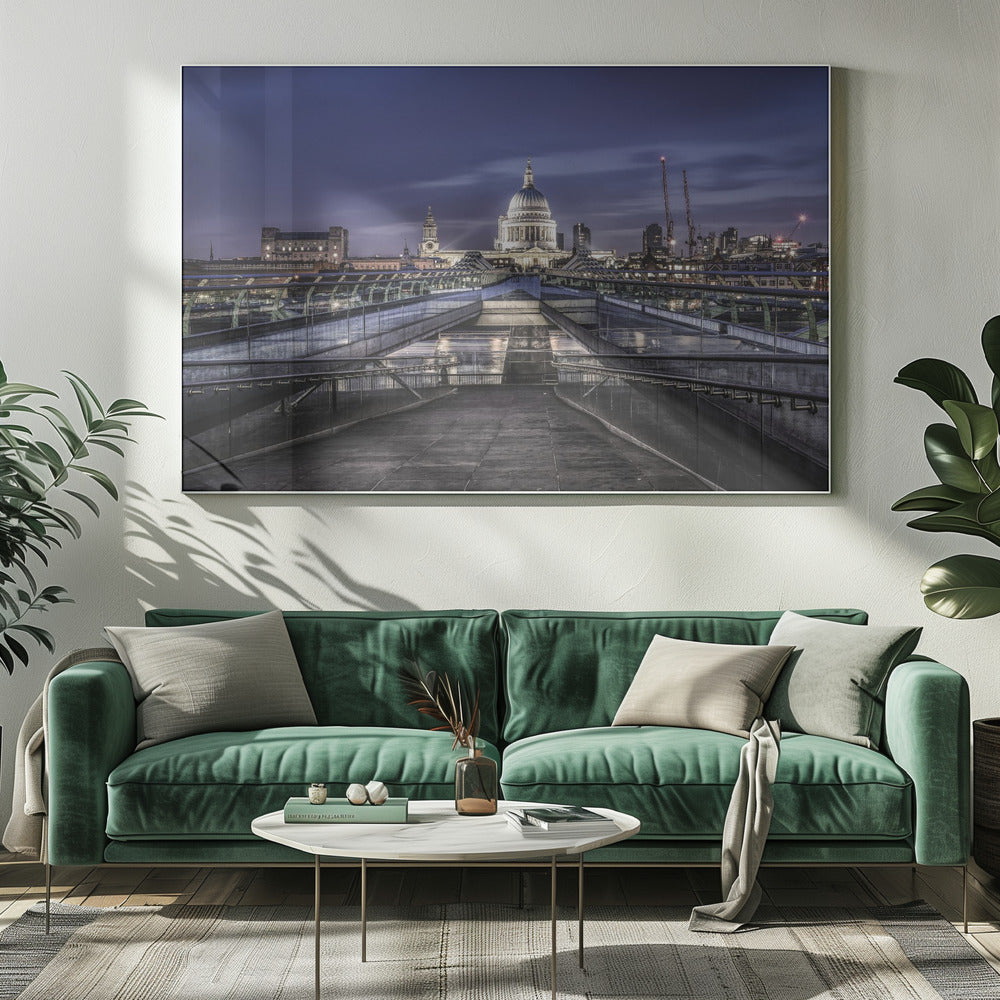 A nighttime photograph from the Millennium Bridge leading towards the brightly illuminated St. Paul's Cathedral against a dark blue twilight sky in London, all enclosed in a silver frame. Poster