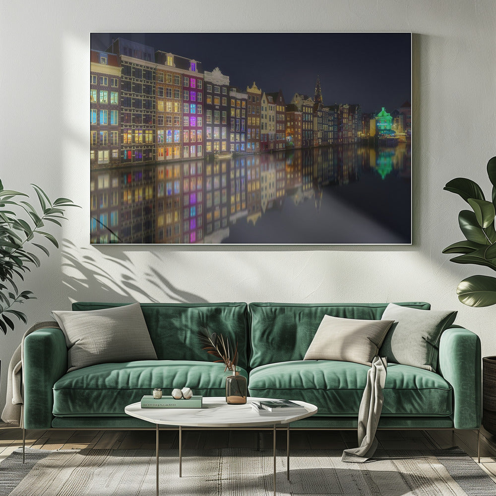 A vibrant nighttime photograph of colorful canal houses in Amsterdam, with their glowing lights beautifully reflected in the still water of the canal below, all framed in silver. Print
