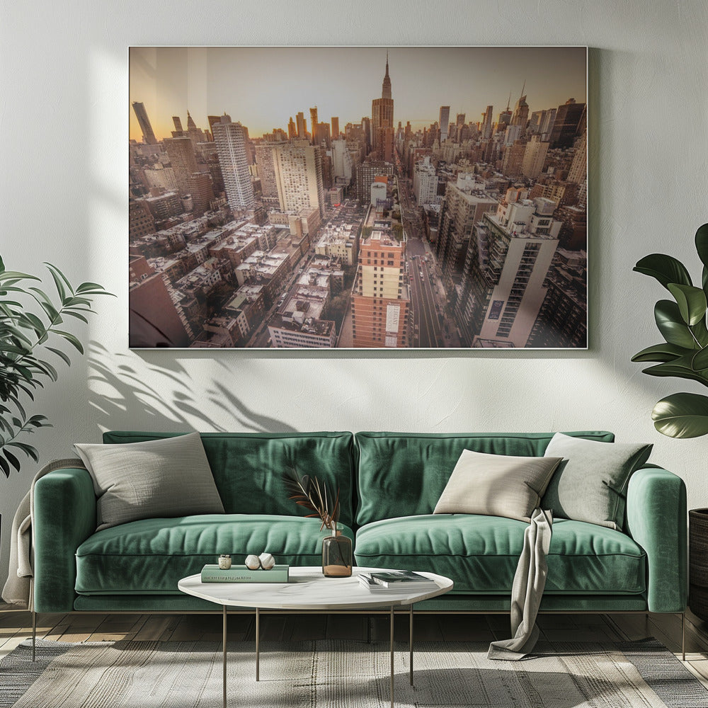 An aerial photograph of the New York City skyline at sunset, with the Empire State Building prominent against the glowing sky. The warm light of the setting sun bathes the dense urban landscape in a golden hue. The entire scene is enclosed in a silver, brushed metal frame. Print