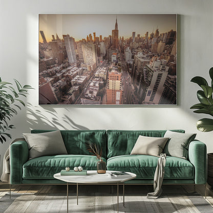 An aerial photograph of the New York City skyline at sunset, with the Empire State Building prominent against the glowing sky. The warm light of the setting sun bathes the dense urban landscape in a golden hue. The entire scene is enclosed in a silver, brushed metal frame. Print