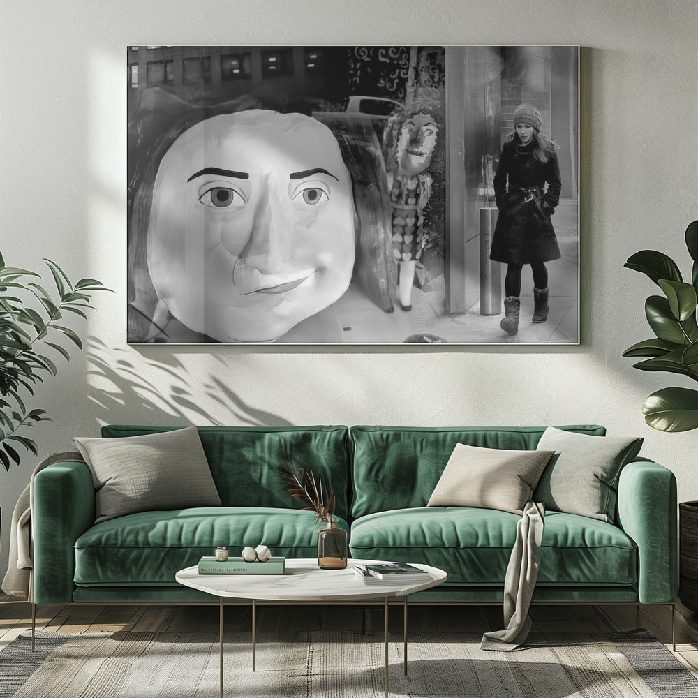 A surreal black and white photograph with a silver frame, featuring a giant, cartoonish head of a historical figure reflected in a window, juxtaposed with a young woman in a winter coat and beanie walking down a city sidewalk. Wall Art