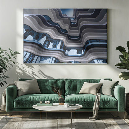 A low-angle view of a modern building with a striking, wavy facade. Alternating bands of light and dark grey create a fluid, ribbon-like pattern, with curved glass windows reflecting the deep blue sky. Artwork