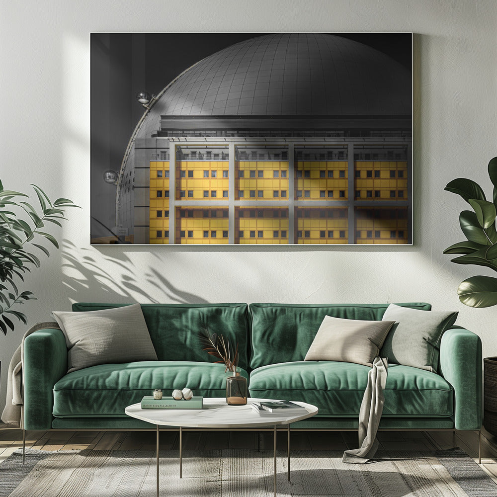 A framed architectural photograph with selective color, featuring a bright yellow building in the foreground against a monochrome background of a large grey dome structure under a black sky. Wall Art