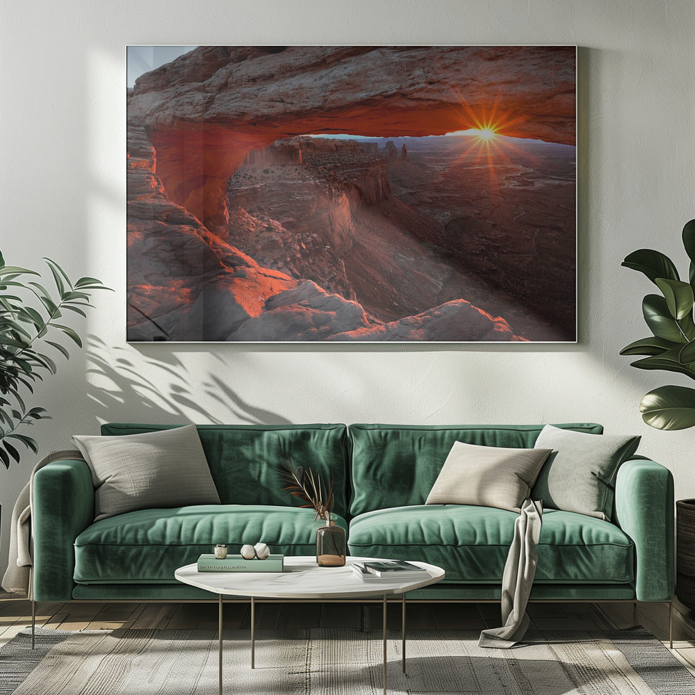A spectacular sunrise seen through the natural frame of Mesa Arch in Canyonlands National Park, Utah. The sun bursts over the horizon, casting a dramatic orange and red glow on the underside of the rock arch and the vast canyon landscape below. Poster