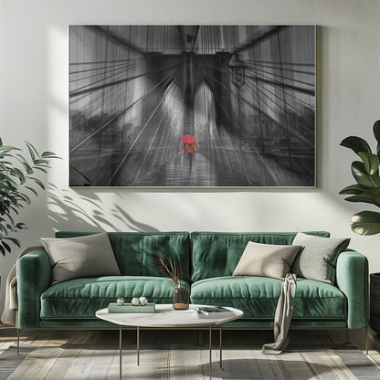A motion-blurred, black and white photo of the Brooklyn Bridge with a person holding a bright red umbrella walking down the center. The selective color makes the red umbrella the focal point against the dramatic, almost abstract lines of the bridge's cables and arches on a wet, reflective walkway. The image is presented in a silver frame. Wall Art