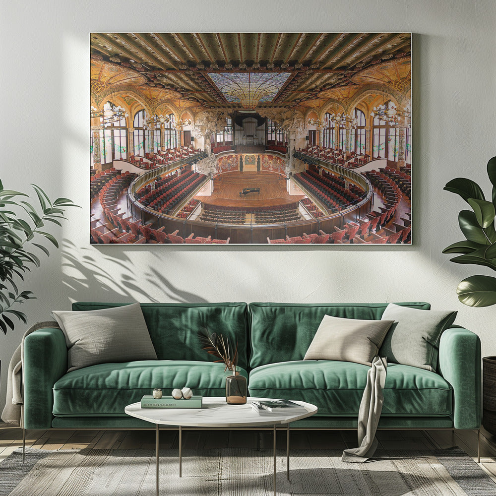 A high-angle, wide shot of the ornate and lavish interior of the Palau de la Música Catalana in Barcelona. The view captures the entire concert hall, with its curved balconies filled with red seats, a central wooden stage with a grand piano, and a spectacular, large stained-glass skylight in the ceiling. Poster