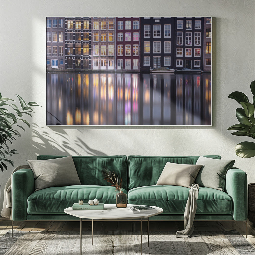 A framed photograph of colorful Amsterdam canal houses at night, their illuminated windows casting vibrant, shimmering reflections on the water below. Artwork