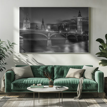 A framed, black and white nighttime photograph of Westminster Bridge in London. The iconic Houses of Parliament and the glowing Big Ben clock tower stand prominently in the background against a dark, cloudy sky. The streetlights on the bridge create starburst effects, and their reflections shimmer on the surface of the River Thames in the foreground. Poster