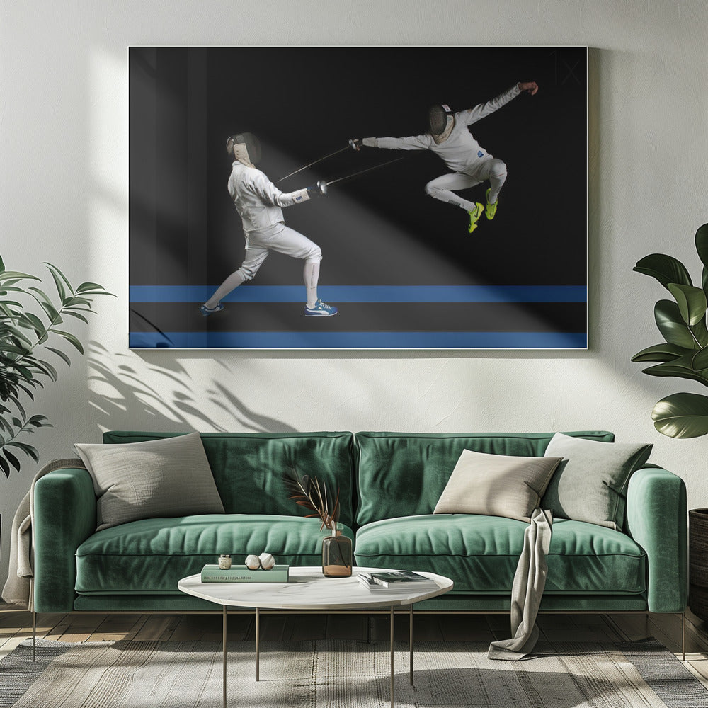 A dynamic action shot of two fencers in full white gear and masks dueling with foils against a stark black background. The fencer on the right is captured mid-air in a dramatic leap, while the fencer on the left lunges forward on a surface marked with blue lines. The image is enclosed in a silver frame. Artwork