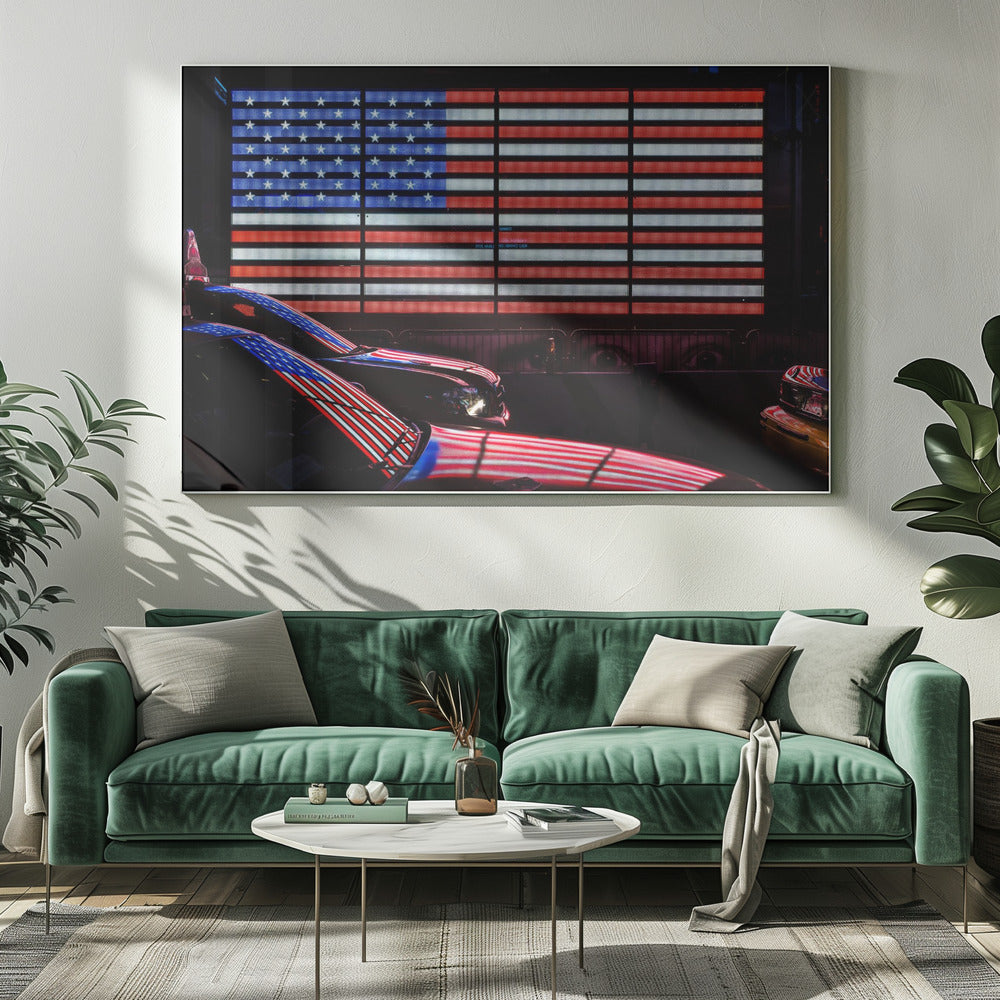 A large illuminated American flag on a billboard at night, with its red, white, and blue lights reflecting on the glossy hoods of two cars in the foreground. Wall Art