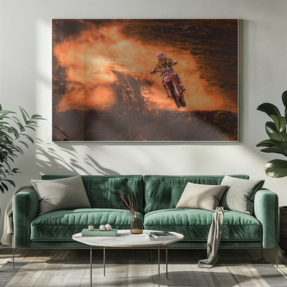 An action-packed photo of a motocross rider in mid-air, jumping their dirt bike over a mound of earth. A large cloud of orange dust billows behind them, creating a dramatic and fiery background. Wall Art