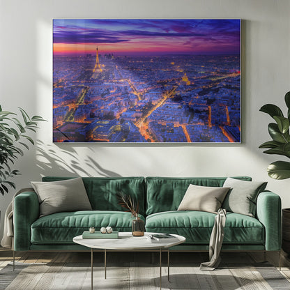 An aerial panoramic view of Paris at dusk, with the cityscape illuminated in cool blue and warm yellow lights. The Eiffel Tower is prominently lit on the left under a dramatic sunset sky transitioning from orange and pink to deep purple. Poster