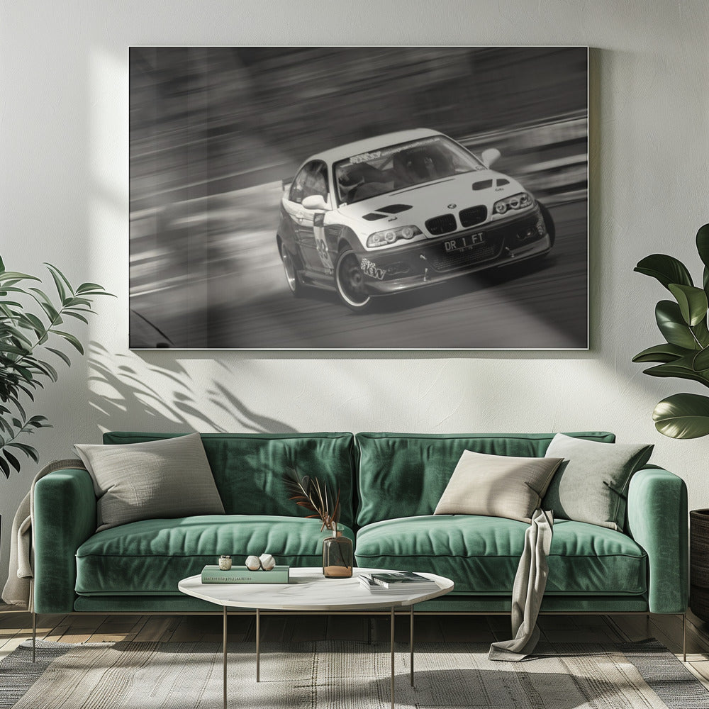 A framed, black and white action photograph of a white and black BMW race car drifting at high speed around a corner. The background is blurred with motion lines, emphasizing the car's speed as it turns, and a puff of smoke is visible from the tires. Wall Art