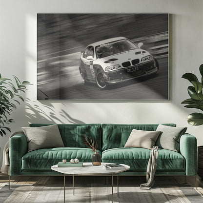 A framed, black and white action photograph of a white and black BMW race car drifting at high speed around a corner. The background is blurred with motion lines, emphasizing the car's speed as it turns, and a puff of smoke is visible from the tires. Wall Art