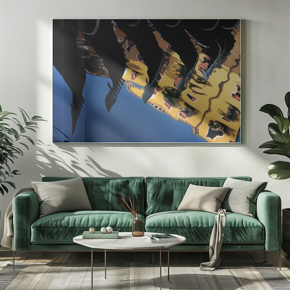 An abstract photograph of a distorted reflection in water, showing a vibrant yellow building against a deep blue sky, with the dark silhouettes of several Venetian gondola prows cutting across the top of the image. The entire scene is enclosed in a silver picture frame. Print