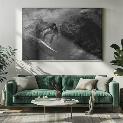 A dramatic black and white photograph of a surfer in a wetsuit skillfully riding down the face of a large, turbulent wave. The image is enclosed in a silver frame. Wall Art