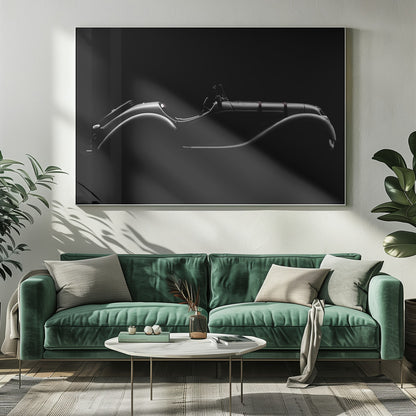A dramatic black and white photograph showcasing the elegant silhouette of a vintage roadster. The side profile of the classic car is highlighted by subtle light, emphasizing its long hood and sweeping fenders against a solid black background, all within a brushed silver frame. Print