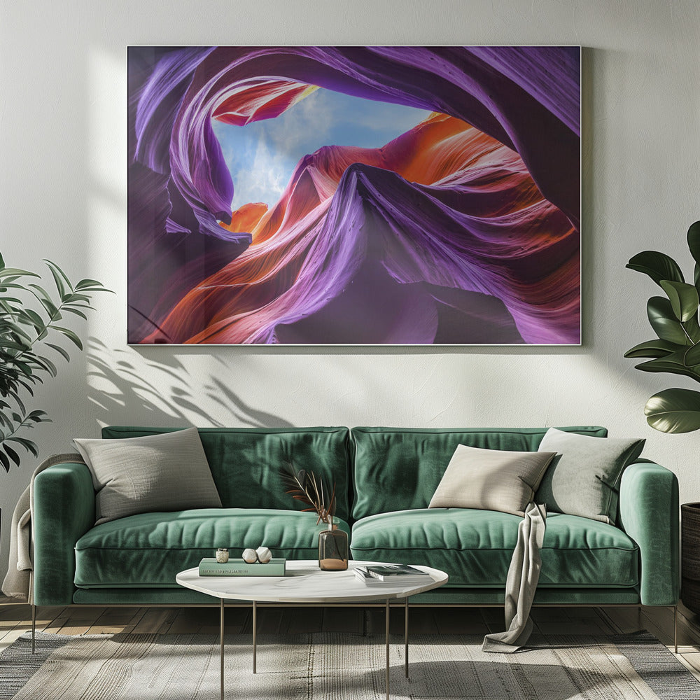 A low-angle photograph looking up from inside a vibrant slot canyon. The smooth, flowing sandstone walls are colored in rich shades of purple, red, and orange, curving around an opening that reveals a bright blue sky with wispy clouds. The image is presented within a silver-colored frame. Wall Art
