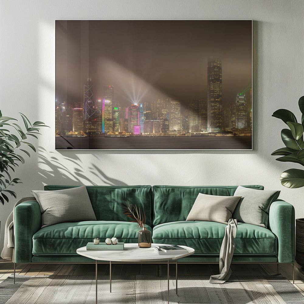 A framed photograph of the Hong Kong skyline at night, viewed from across the water. The skyscrapers are brilliantly lit with yellow, white, and colorful lights, and beams of light shoot up into the foggy, glowing sky. Decor