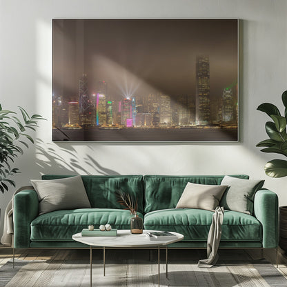 A framed photograph of the Hong Kong skyline at night, viewed from across the water. The skyscrapers are brilliantly lit with yellow, white, and colorful lights, and beams of light shoot up into the foggy, glowing sky. Decor