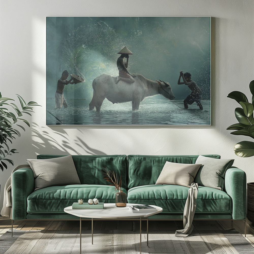 A serene photograph of three young boys playing in a river with a large water buffalo, one boy sits atop the animal while the others splash water, all set against a misty green backdrop and framed in silver. Print