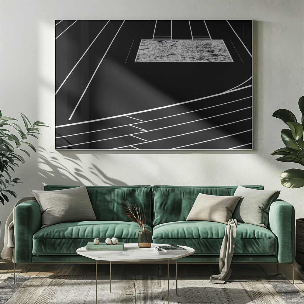 A high-contrast, black and white abstract artwork depicting a running track from an elevated perspective. Stark white lines representing lanes curve across a solid black background. In the upper portion, a rectangular shape filled with a textured, water-like pattern replaces a typical sand pit. The entire piece is presented within a silver frame. Print