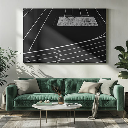 A high-contrast, black and white abstract artwork depicting a running track from an elevated perspective. Stark white lines representing lanes curve across a solid black background. In the upper portion, a rectangular shape filled with a textured, water-like pattern replaces a typical sand pit. The entire piece is presented within a silver frame. Print