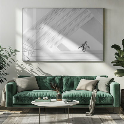 A minimalist black and white photograph in a silver frame, featuring a lone BMX rider performing a trick on the back wheel inside a stark, modern building with strong diagonal architectural lines. Poster